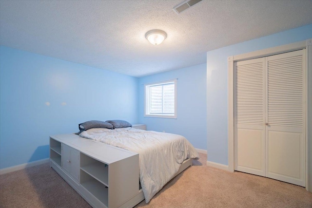 carpeted bedroom with a closet and a textured ceiling