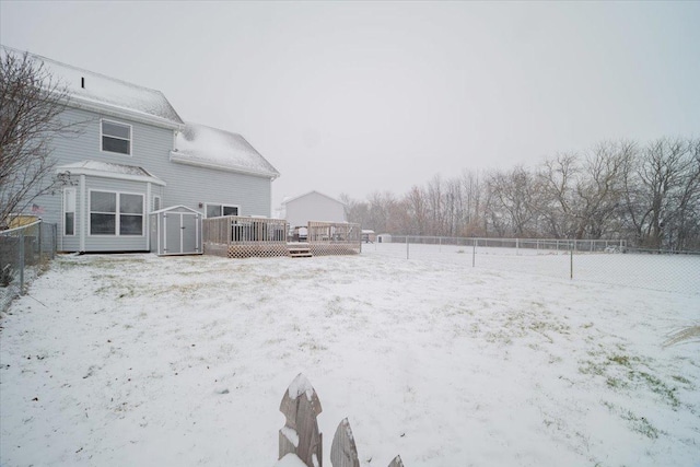 yard layered in snow with a deck and a shed