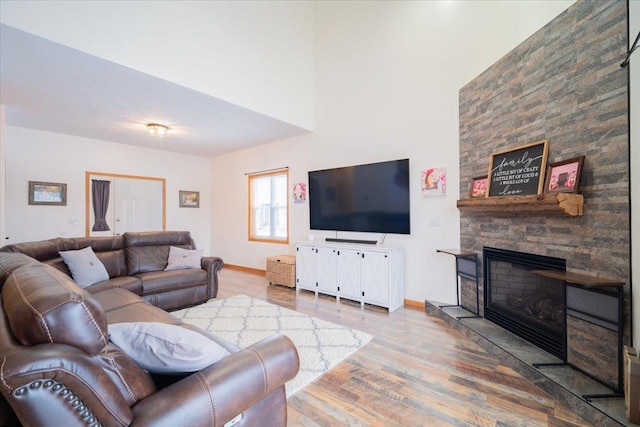 living room with wood-type flooring and a stone fireplace