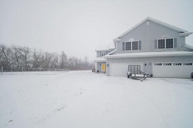 snow covered rear of property with a garage