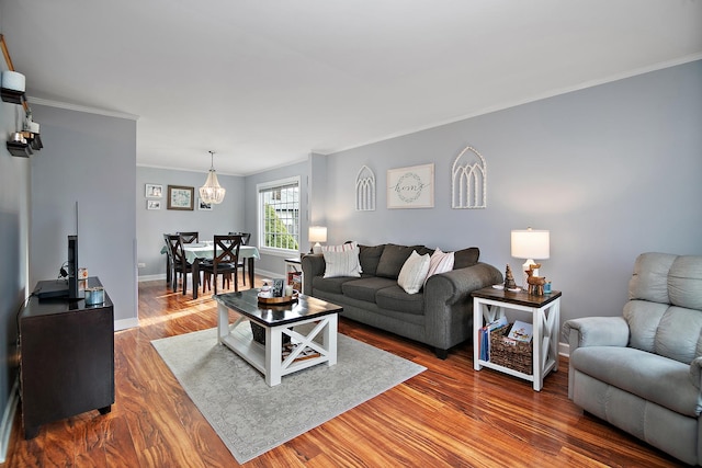 living room featuring a notable chandelier, wood-type flooring, and crown molding