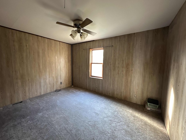 spare room with carpet, ceiling fan, and wood walls