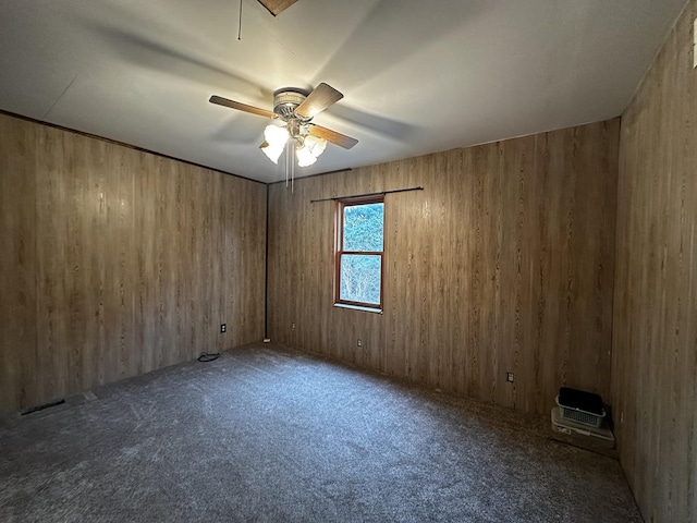 carpeted empty room featuring ceiling fan and wood walls