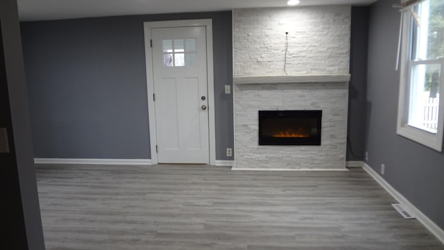 entryway with hardwood / wood-style floors, a healthy amount of sunlight, and a stone fireplace