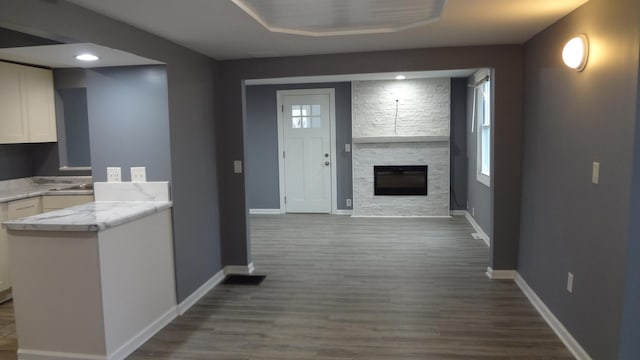 kitchen featuring white cabinets, hardwood / wood-style flooring, and a stone fireplace