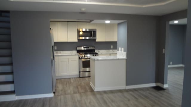 kitchen with white cabinetry, stainless steel appliances, and light hardwood / wood-style flooring