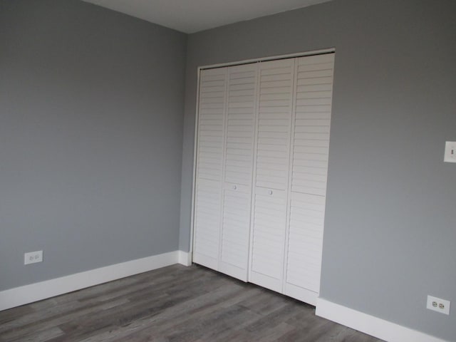 unfurnished bedroom featuring a closet and dark wood-type flooring