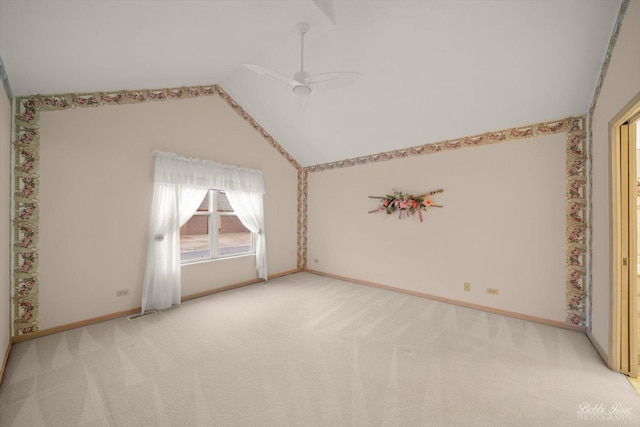 spare room featuring light colored carpet, vaulted ceiling, and ceiling fan