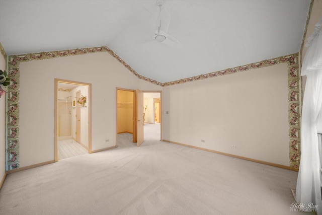 unfurnished bedroom featuring light carpet, vaulted ceiling, ceiling fan, a spacious closet, and a closet