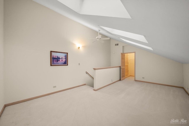 additional living space with lofted ceiling with skylight, ceiling fan, and light colored carpet