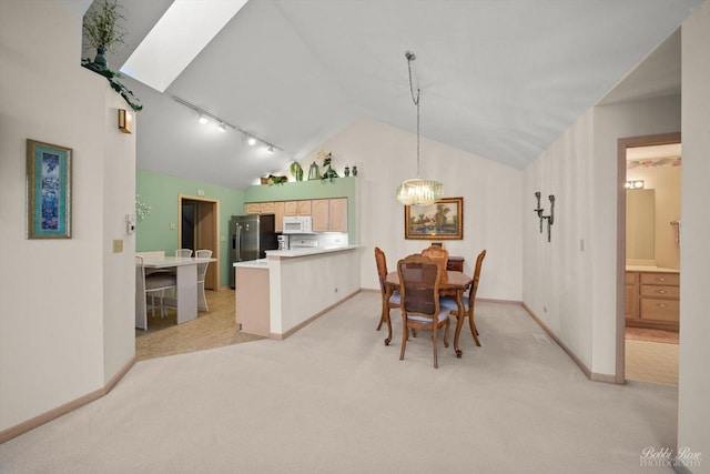 carpeted dining area with rail lighting, an inviting chandelier, and vaulted ceiling