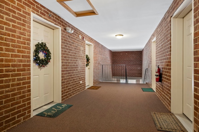 hall featuring carpet and brick wall