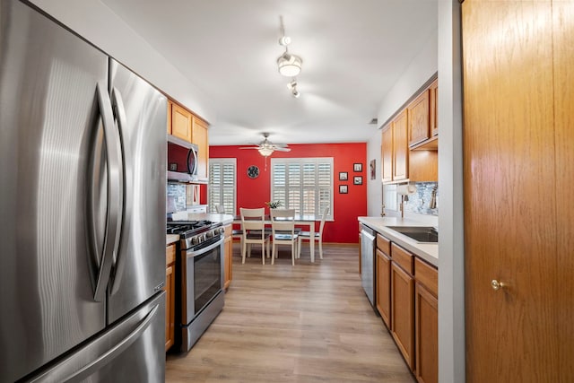 kitchen featuring decorative backsplash, light hardwood / wood-style flooring, ceiling fan, and appliances with stainless steel finishes