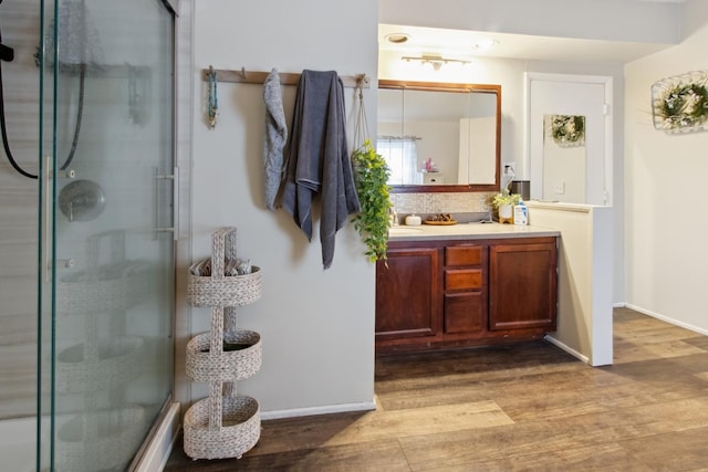 bathroom with hardwood / wood-style floors, vanity, and a shower with shower door