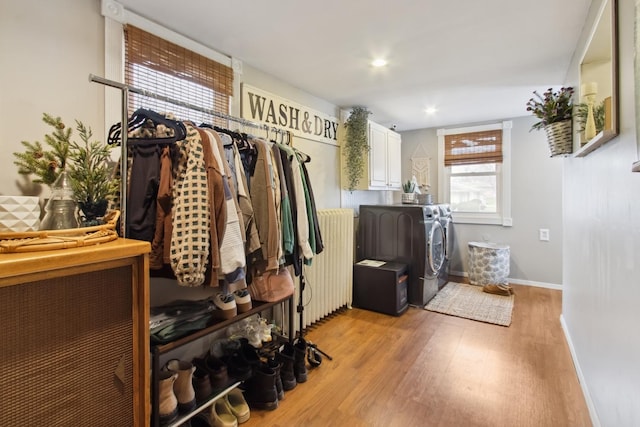 spacious closet with light wood-type flooring, radiator heating unit, and washing machine and clothes dryer