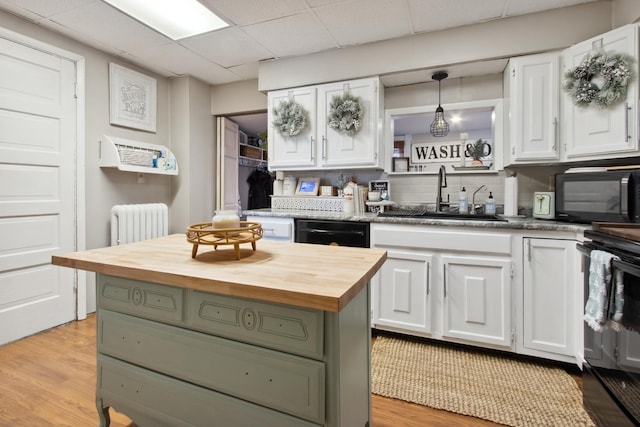 kitchen with white cabinets, decorative light fixtures, butcher block countertops, and sink