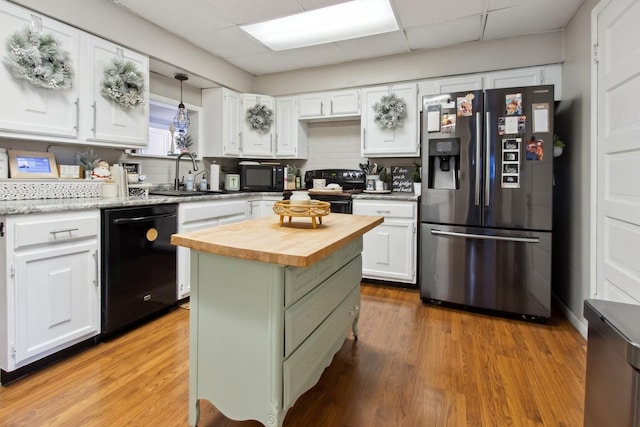 kitchen with sink, a kitchen island, light hardwood / wood-style floors, white cabinets, and black appliances