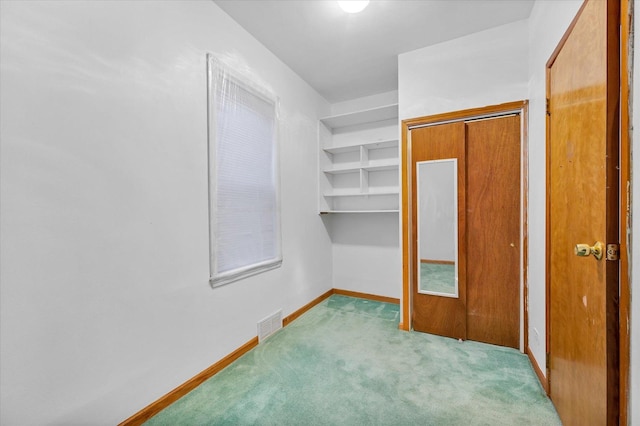 walk in closet with light carpet