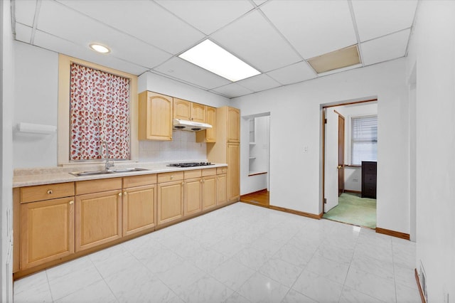 kitchen featuring a paneled ceiling, light brown cabinets, backsplash, sink, and gas stovetop