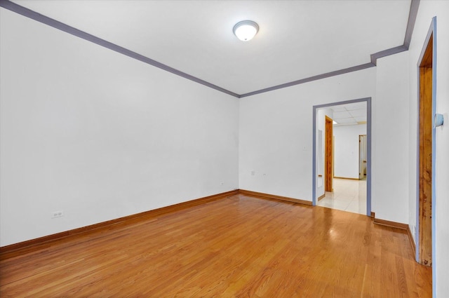 empty room featuring light wood-type flooring and crown molding