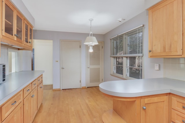 kitchen with pendant lighting, backsplash, light brown cabinets, and light hardwood / wood-style flooring