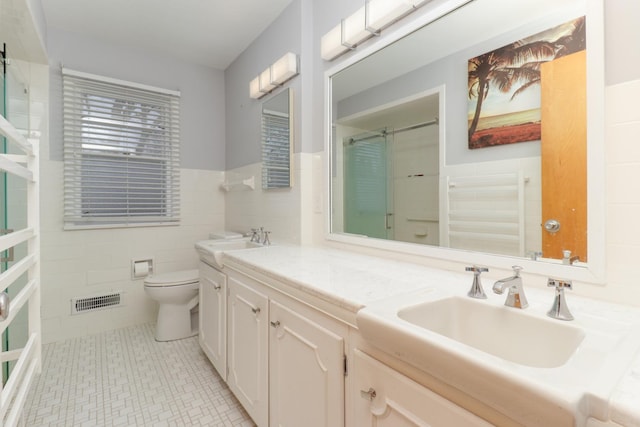 bathroom with walk in shower, vanity, toilet, and tile walls