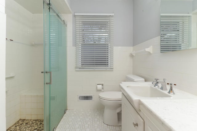 bathroom featuring tile walls, an enclosed shower, vanity, tile patterned floors, and toilet