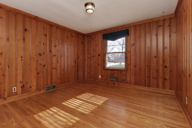 empty room with wooden walls and light hardwood / wood-style floors