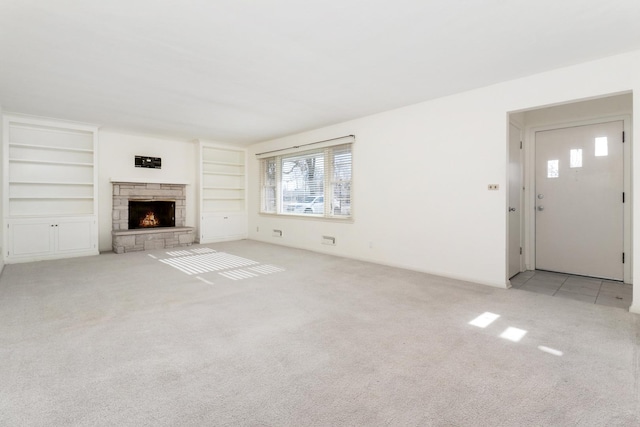 unfurnished living room with light colored carpet and a stone fireplace