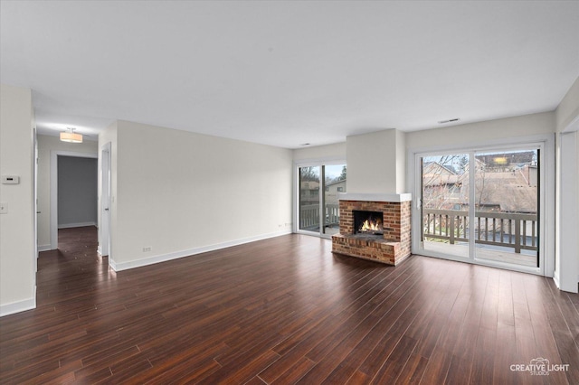 unfurnished living room featuring a fireplace, a wealth of natural light, and dark hardwood / wood-style flooring