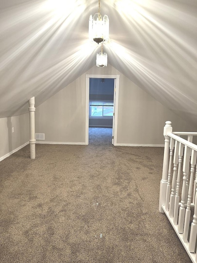 additional living space featuring dark carpet, lofted ceiling, and a chandelier