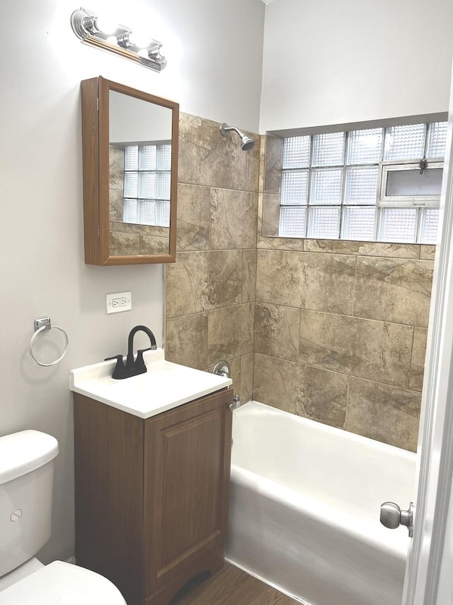 bathroom featuring wood-type flooring, tiled shower / bath combo, and toilet