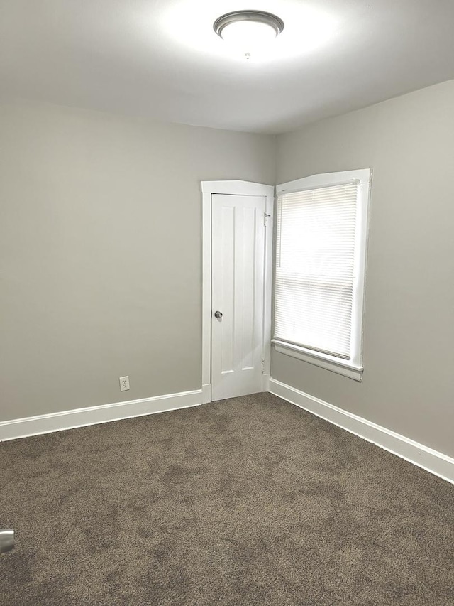 spare room with dark colored carpet