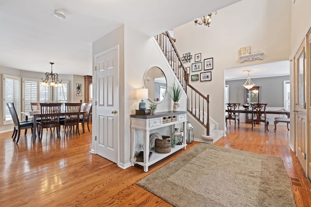 entryway featuring baseboards, stairs, a chandelier, and wood finished floors