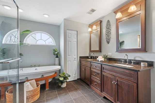 bathroom featuring double vanity, a freestanding tub, a sink, and visible vents