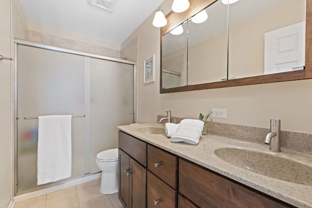 bathroom with double vanity, a stall shower, a sink, and toilet