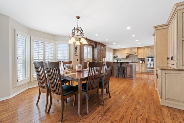 dining area featuring baseboards, recessed lighting, an inviting chandelier, and light wood-style floors