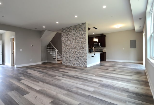 unfurnished living room with electric panel and light hardwood / wood-style flooring