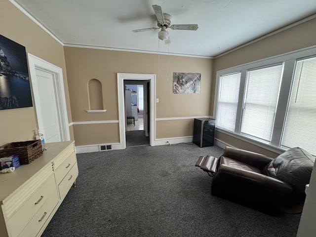 sitting room featuring dark colored carpet, ceiling fan, and crown molding