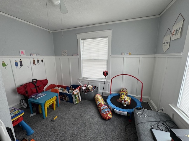 rec room featuring crown molding, ceiling fan, a healthy amount of sunlight, and a textured ceiling