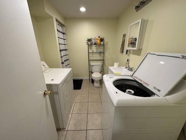 laundry area featuring light tile patterned floors, separate washer and dryer, and sink