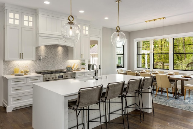 kitchen featuring white cabinetry, stainless steel stove, a kitchen island with sink, and dark hardwood / wood-style floors