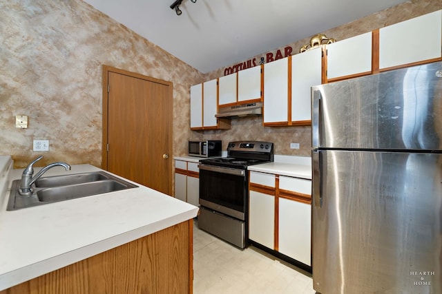 kitchen with appliances with stainless steel finishes, track lighting, white cabinets, and sink