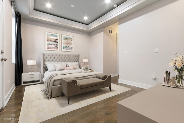 bedroom with dark hardwood / wood-style floors and a tray ceiling