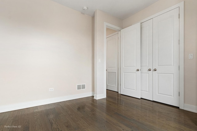 unfurnished bedroom featuring dark hardwood / wood-style flooring and a closet