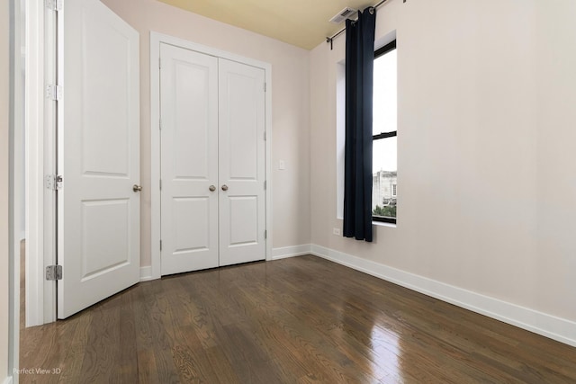 unfurnished bedroom featuring dark hardwood / wood-style floors and a closet