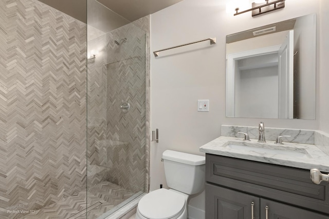 bathroom with vanity, toilet, and tiled shower