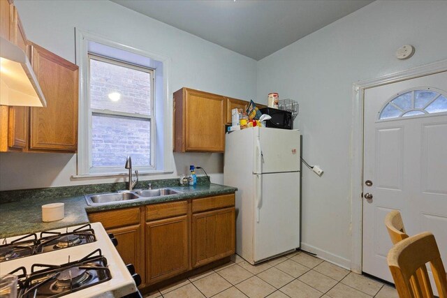 kitchen with sink, light tile patterned flooring, exhaust hood, and white appliances