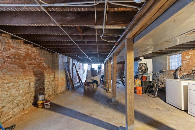 basement featuring washer and dryer and brick wall