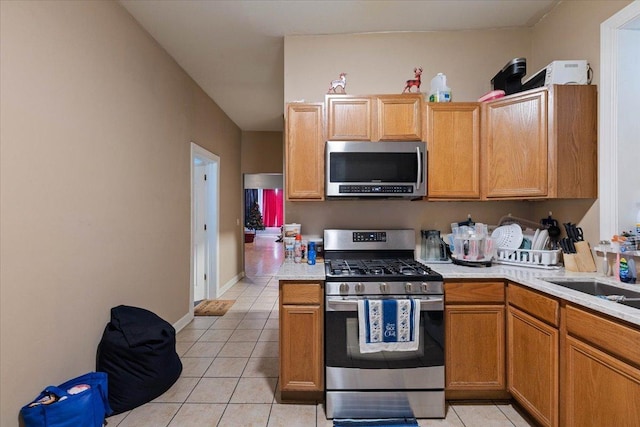 kitchen with sink, light tile patterned flooring, and appliances with stainless steel finishes